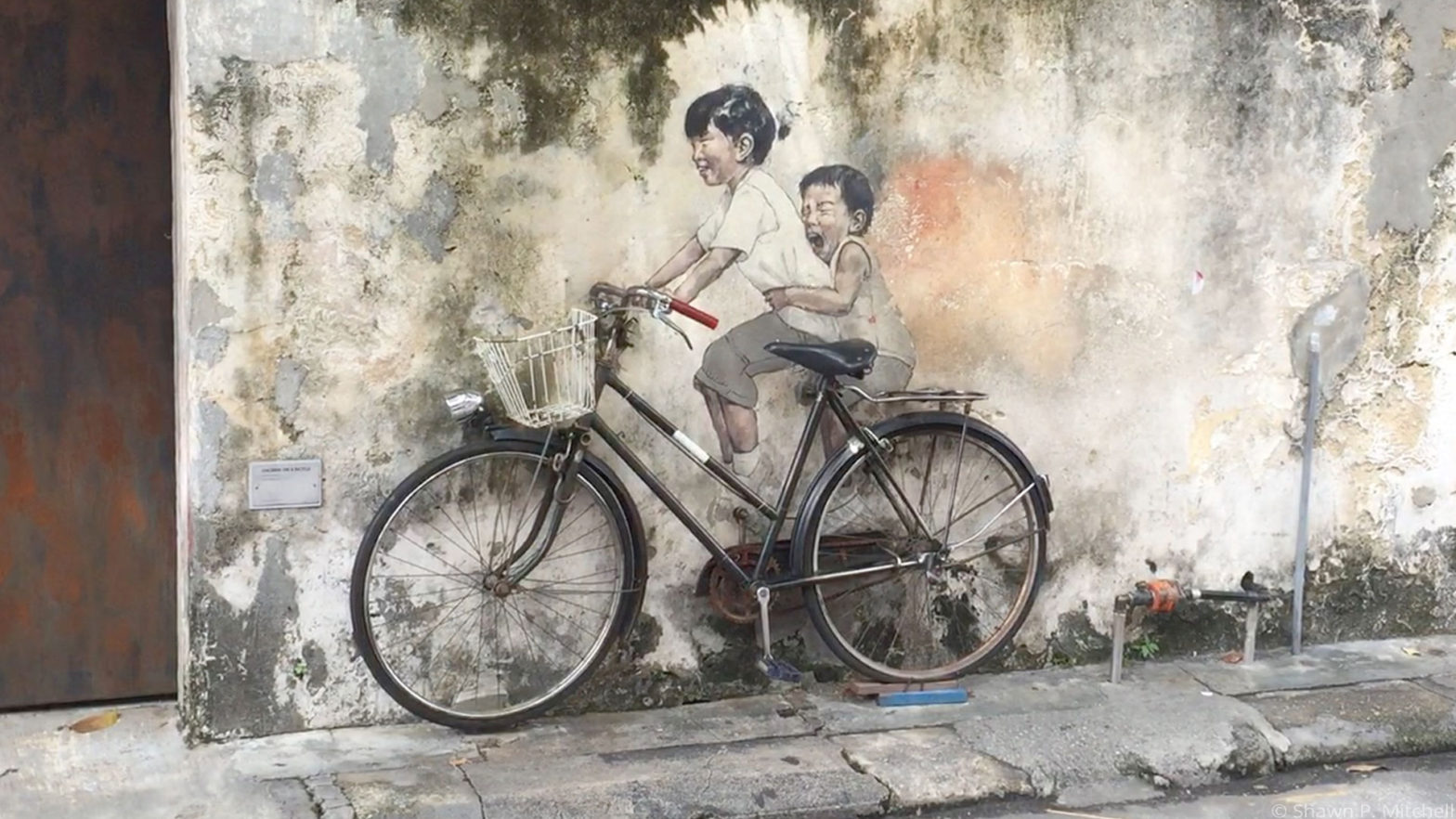 A 3D mural of a young girl and a boy on a bike in Georgetown, Malaysia.